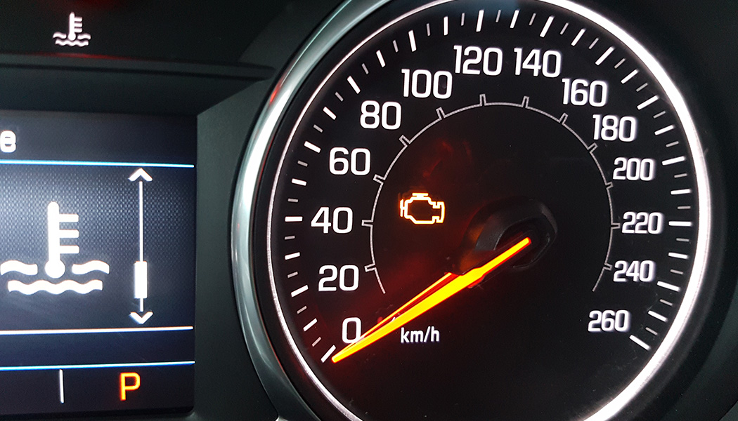 Closeup of a vehicle's illuminated check engine light and dashboard