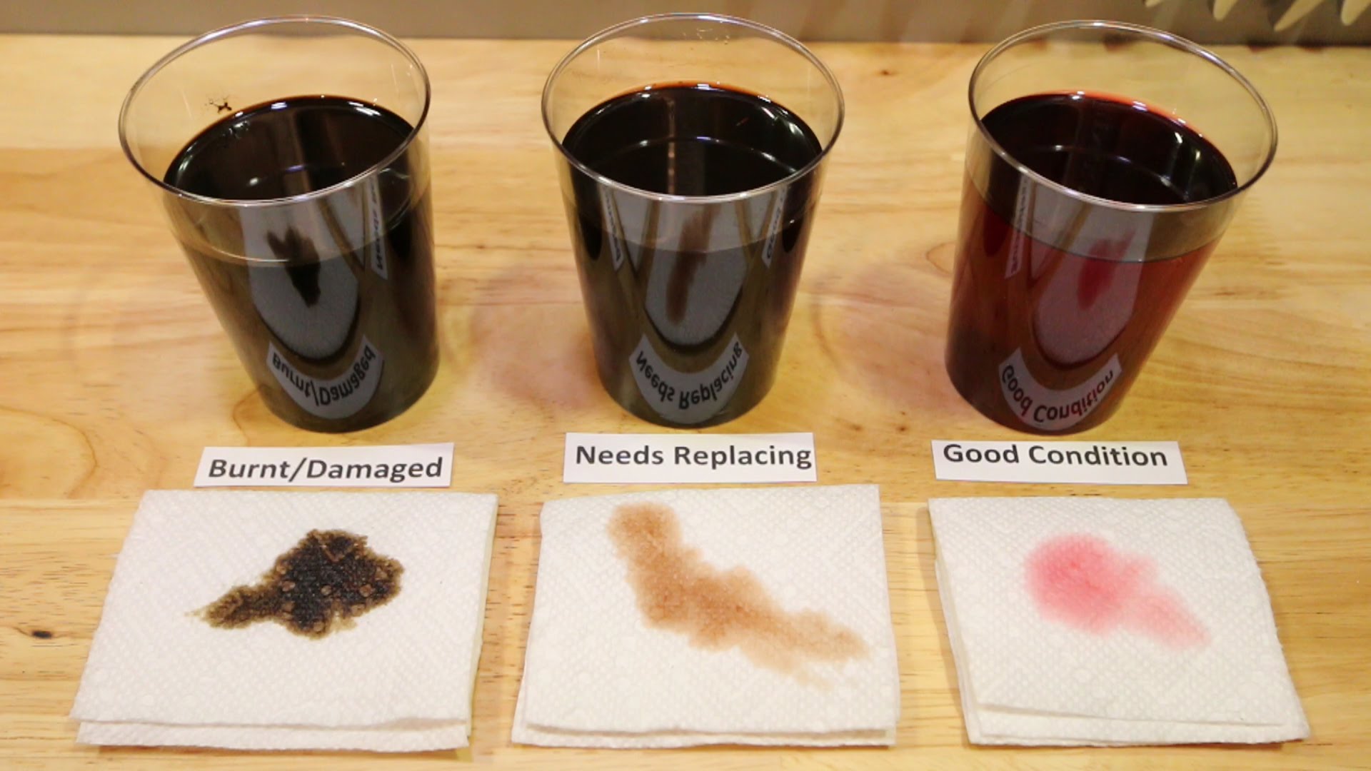 Three different states of transmission fluid being shown, one in good condition, one needing replacement, and the other being burnt and damaged.