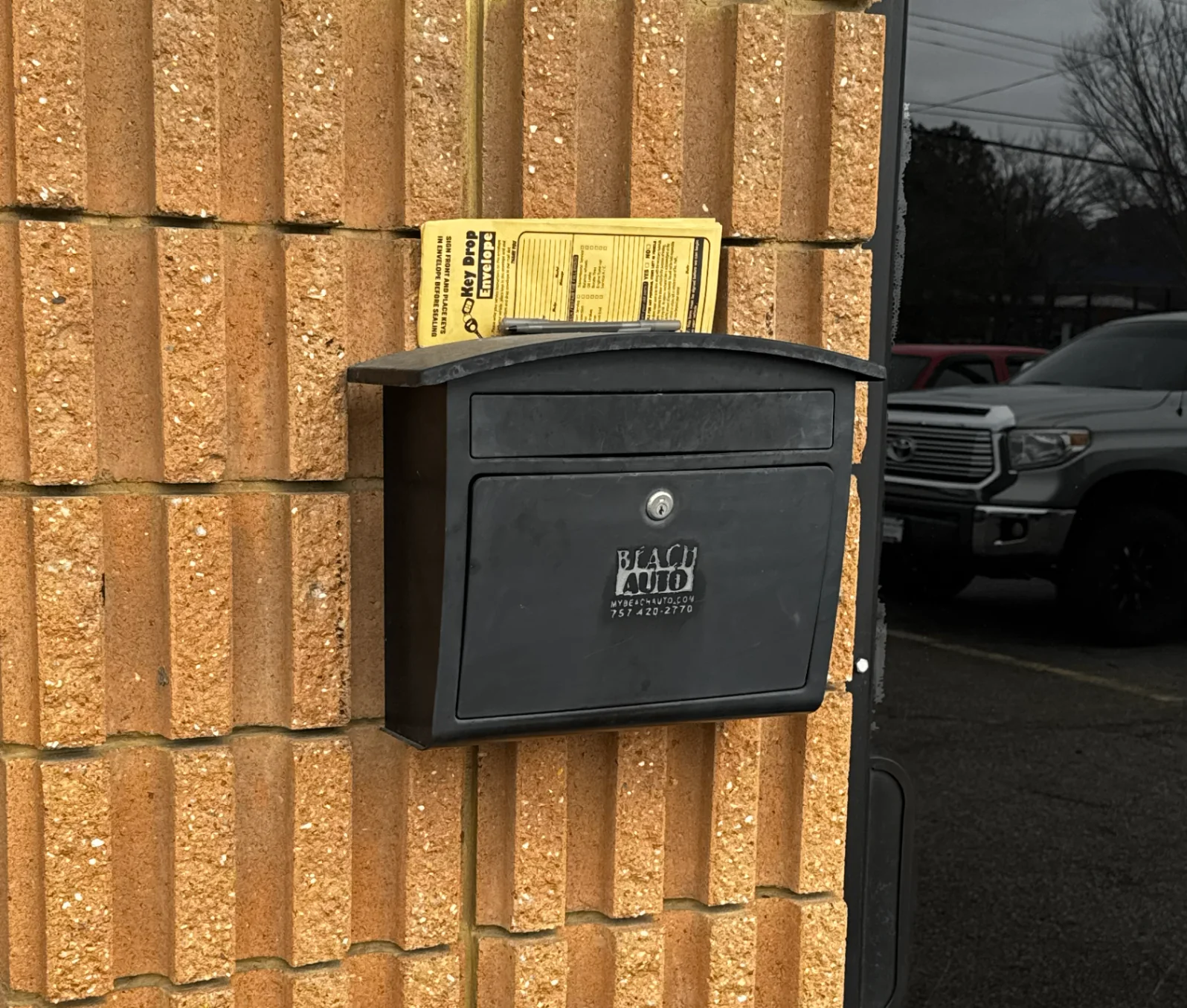 Secure key drop box mounted on the brick wall next to the front entrance