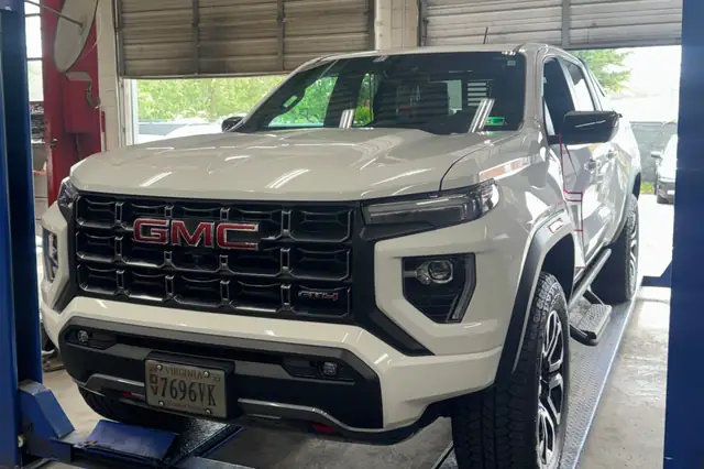 White GMC Canyon pickup raised on a lift for truck service at Beach Auto & Transmission Repair in Virginia Beach