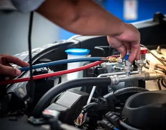 Mechanic connecting AC refrigerant hoses to a vehicle engine at Beach Auto Repair in Virginia Beach